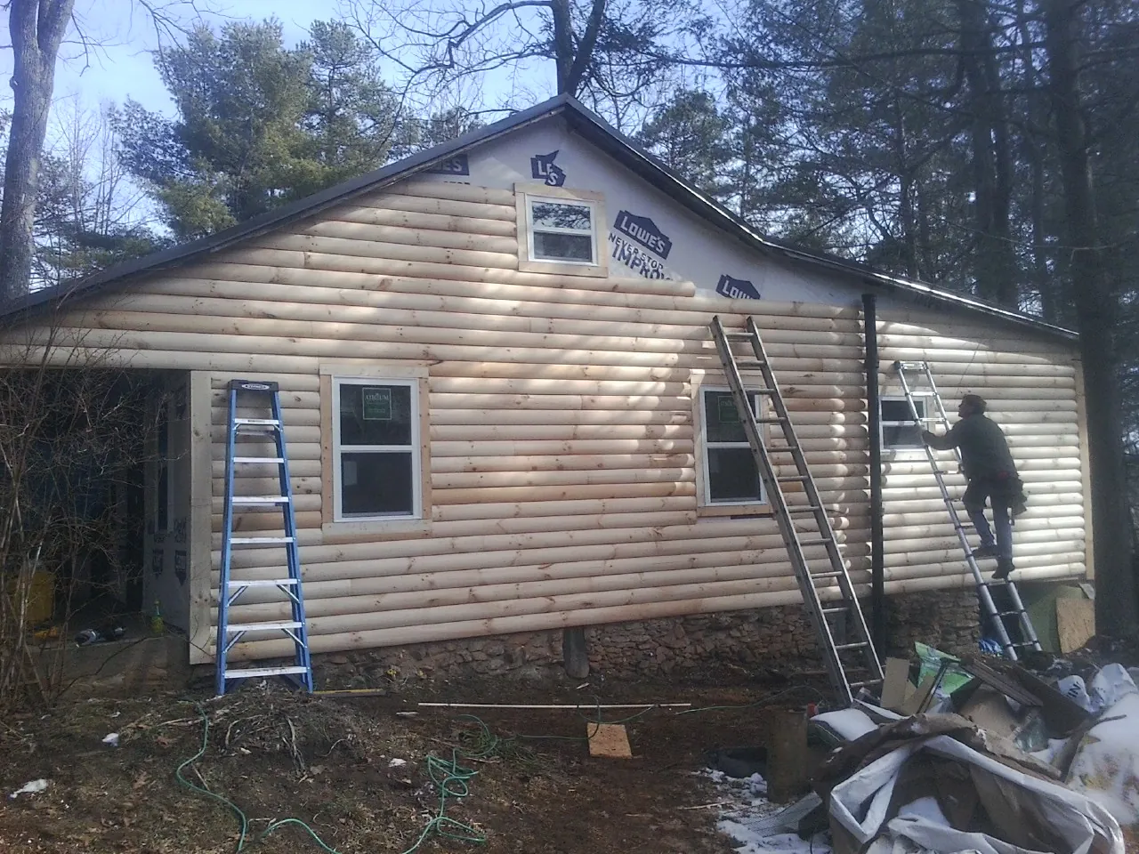 Ladders set against fresh log siding during an exterior remodel in Brewster