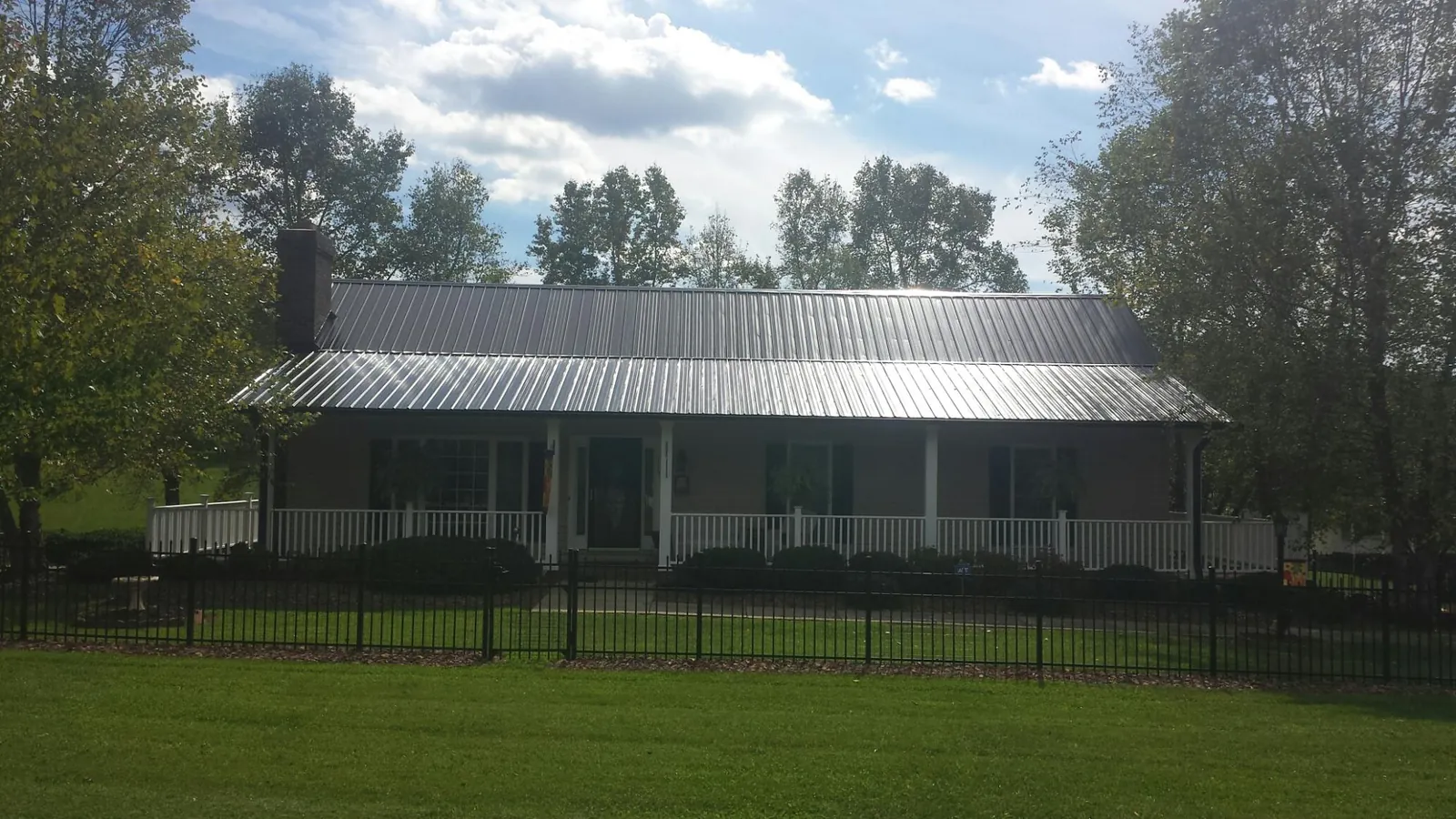 Gray metal roof on a brick ranch with a full width front porch — Gutter Guard Installation work by our crew in Brewster