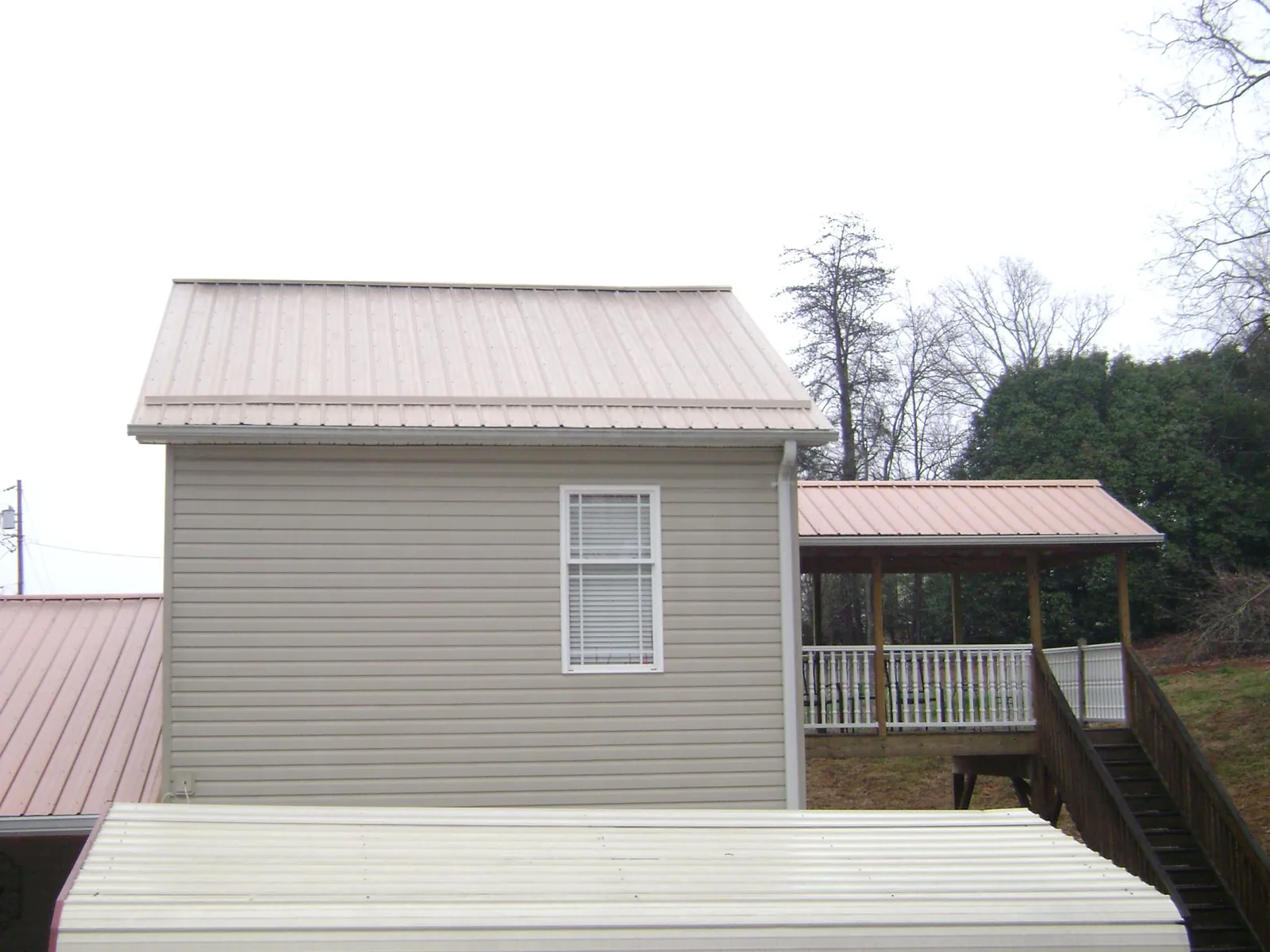 Tan metal roofs on a two story addition and attached porch, from a Roof Replacement job in Brewster